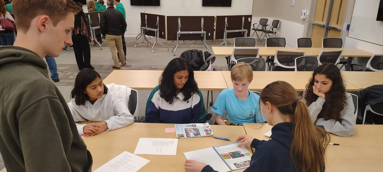 FAMNM members reviewing an engineering notebook with an FTC team